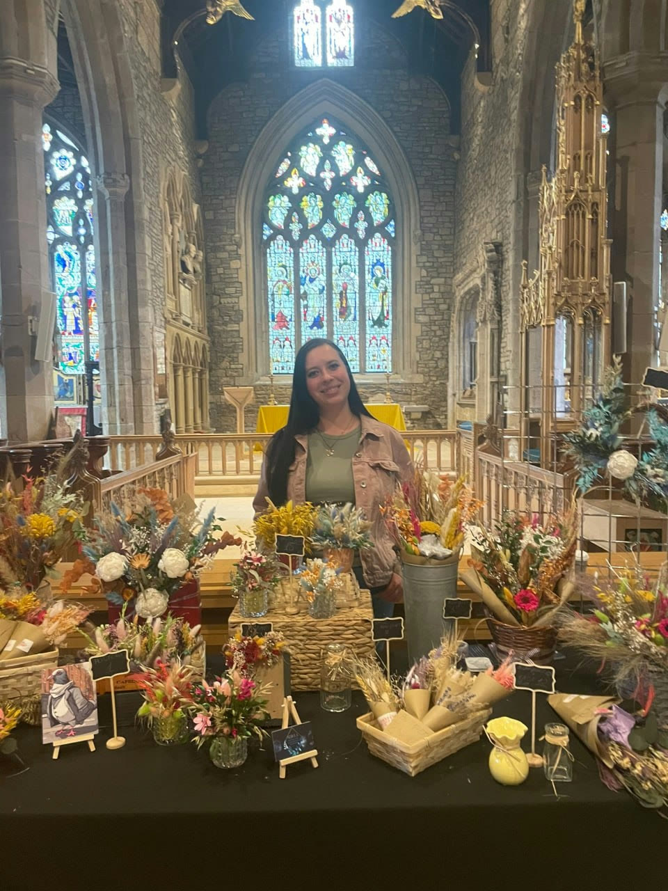 Mariya displaying Petal Ritual floral pieces at a market