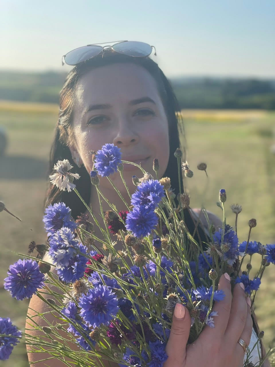 Mariya holding blue cornflowers in a field