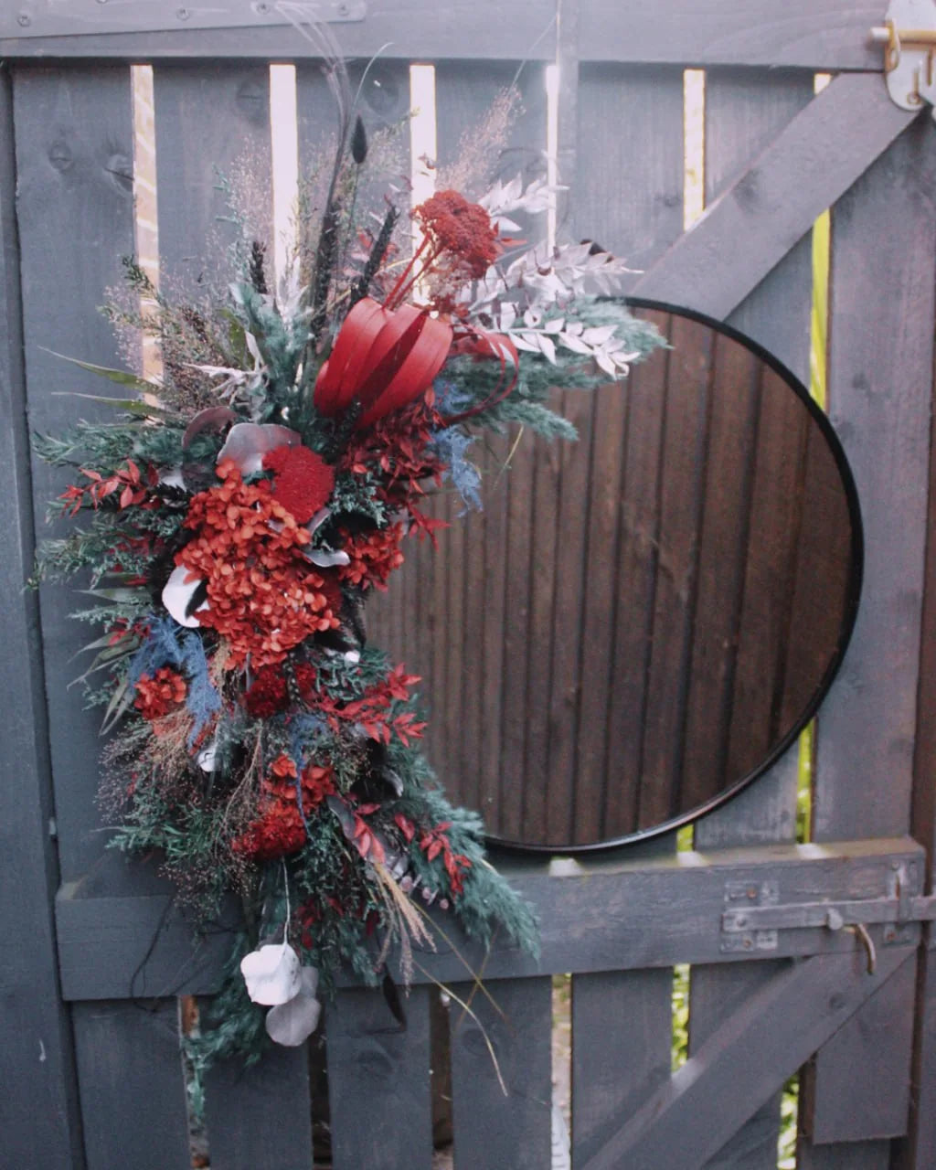 Asymmetric red dried-flower installation on a round mirror