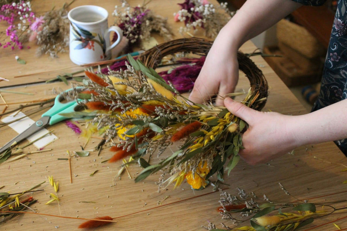 A guest creating a colourful dried-flower wreath at a Petal Ritual workshop